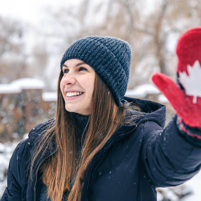 happy-young-woman-red-mittens-with-flag-canada-snowy-weather